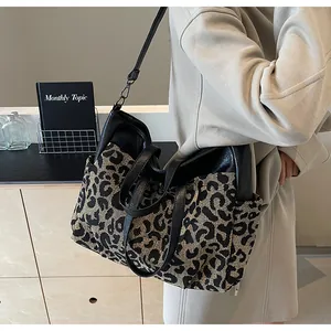 Détail du cabas en toile léopard avec bordures en cuir noir et poches latérales