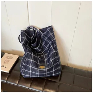 Detail of blue plaid canvas tote bag with golden handmade badge on leather stool