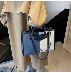 Vista detallada del bolso tote de lona y denim con ribetes de cuero azul y asas