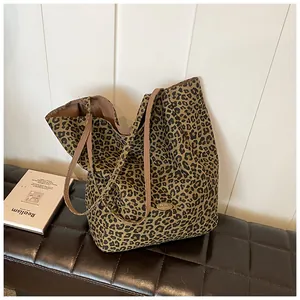 Detail of leopard print tote bag with brown straps and handmade logo on a leather seat