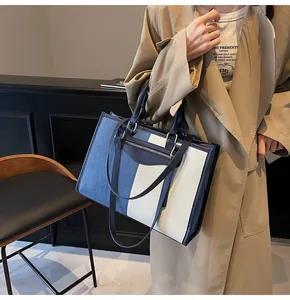 Vista detallada del bolso tote de denim y lona con asas de cuero y correa larga para el hombro