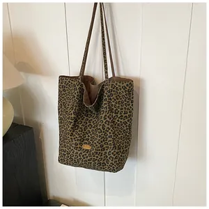 Macro detail of leopard print canvas tote bag featuring a polished gold brand emblem