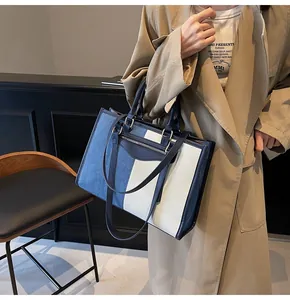 Detalle del bolso tote de denim y lona beige combinado con una gabardina para el uso diario