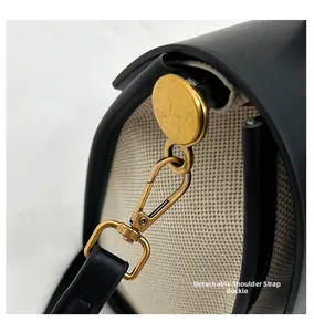 Detail of detachable gold matte buckle on retro canvas and black leather crossbody bag