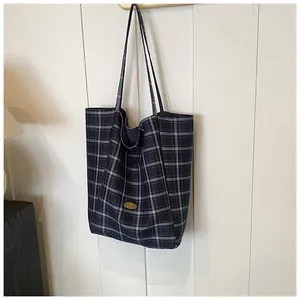Detail of dark blue plaid tote bag with handmade metal badge and soft canvas texture