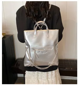 Detail of silver metallic PU backpack with rivets and chunky chain strap on model
