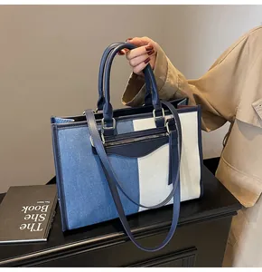 Detalle del bolso tote de lona bicolor con correa ajustable y acabados metálicos plateados