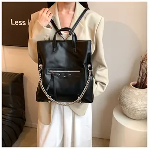 Close-up of black leather backpack with silver studs and chain details on a model
