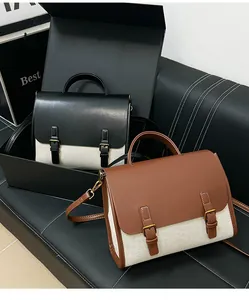 Detail of vintage messenger bags in black and brown leather with canvas contrast panel