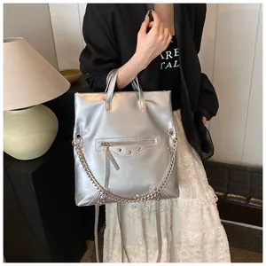 Detailed view of metallic silver tote bag with punk studs and decorative zippers