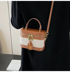 Dettaglio della borsa vintage in tela bicolore con manico in pelle e zip dorata