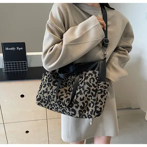 Détail du sac cabas léopard avec poignées en cuir noir et bandoulière réglable