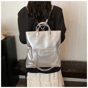 Detailed view of silver metallic fashion backpack with metal chains on female model