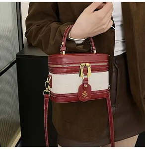 Dettaglio borsa a scatola in pelle rossa e tela con finiture dorate e targhetta