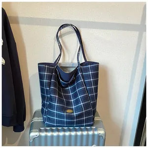 Detail of blue plaid canvas tote bag with gold Handmade plaque on silver luggage