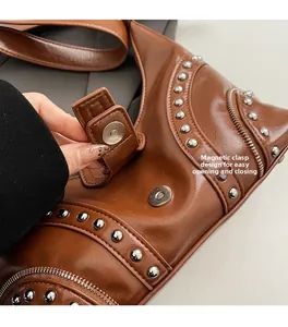 Détail du fermoir magnétique sur un sac à bandoulière marron orné de rivets argentés