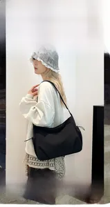 Detail of a black nylon shoulder bag with side drawstring and spacious storage compartments