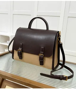 Detail of retro contrasting faux leather and canvas messenger bag with gold buckles