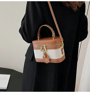 Dettaglio borsa a scatola in tela a contrasto con targhetta rotonda e zip in metallo