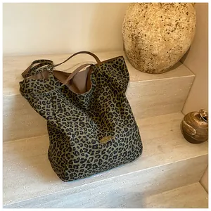 Close-up of leopard print tote bag with handmade metal plaque on stone background