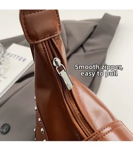 Détail du zip en métal lisse et rivets argentés sur sac à bandoulière en cuir marron