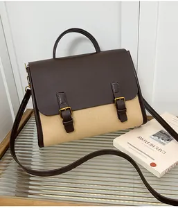 Detail of vintage beige canvas and brown leather satchel with dual buckle straps