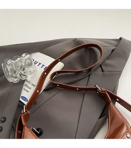 Gros plan sur la bandoulière en cuir marron réglable avec clous et boucles métalliques