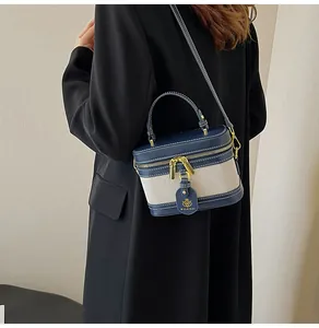 Dettaglio borsa a scatola in pelle blu marina e tela beige con finiture oro