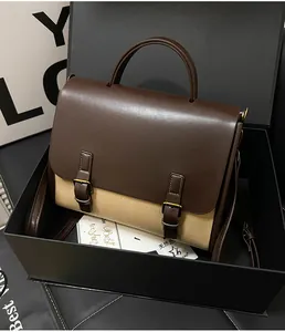 Detailed close-up of a vintage brown and beige canvas handbag inside a black luxury gift box