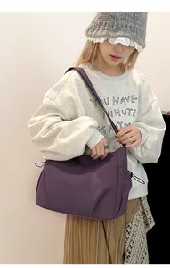 Side view of a deep purple nylon crossbody bag featuring stylish drawstring detailing