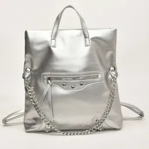 Silver metallic mini backpack and handbag with chains and rivets on white background