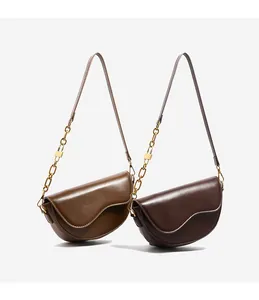 Detail of saddle crossbody bags with asymmetric wavy edges and gold chain straps