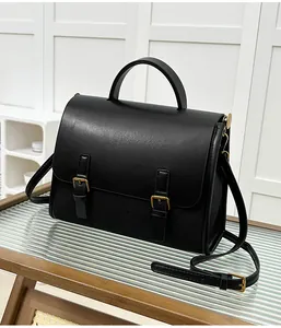 Detailed macro view of black faux leather vintage messenger bag with gold metal hardware