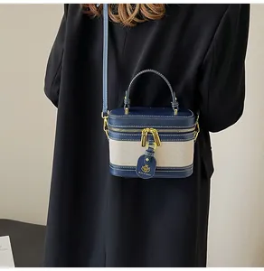 Dettaglio di una borsa vintage box in pelle blu e tela indossata da un modello