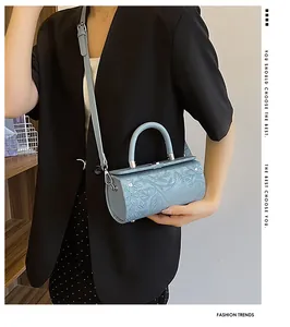 Close-up of light blue cylindrical barrel bag featuring 3D floral embossed leather details