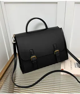 Detail of retro black satchel bag with gold buckles on a stylish glass table