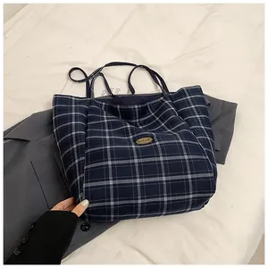 Detail of blue plaid canvas tote bag with a handmade gold emblem and slim shoulder straps