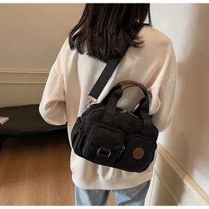 Detail of black nylon crossbody bag with multi-pockets and adjustable strap shown on model