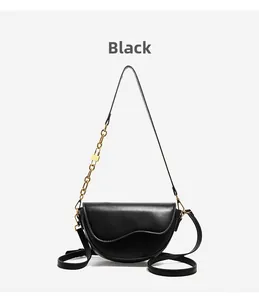 Detail of black saddle bag with golden chain, metal lock charm and adjustable strap