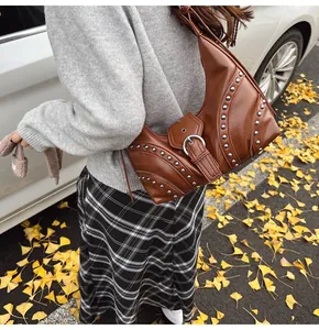 Détail d'un sac à bandoulière en similicuir marron avec clous et boucle métallique