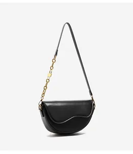Detail of black saddle bag featuring unique wavy flap and golden chain strap link