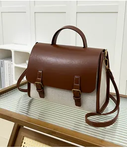 Detail view of retro canvas and brown leather messenger bag with metal buckle closure