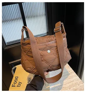 Detailed macro view of brown quilted nylon crossbody bag with woven texture and logo
