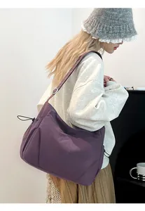 Detail of purple nylon crossbody bag with drawstring side and adjustable shoulder strap