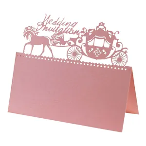 Close-up of laser-cut royal carriage and Wedding Invitation text on pink place card