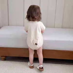 Barboteuse bébé en coton blanc cassé avec détail de queue d'animal au dos de la pièce