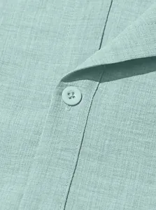 Macro shot of mint green linen shirt collar showing texture and resin button detail