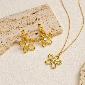 Gros plan sur l'ensemble boucles d'oreilles et collier fleur dorée sur pierre beige