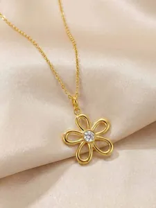 Gros plan détaillé du pendentif fleur dorée avec pierre en zircon sur un tissu en satin