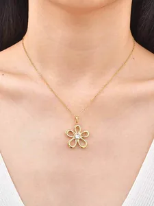 Gros plan d'un collier pendentif fleur évidée en or avec cristal sur mannequin femme